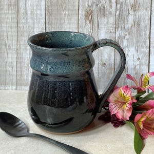 Artisan stoneware mug beside small flowers