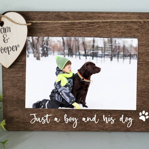 May include: A wooden photo frame with a heart-shaped plaque that says "Liam & Cooper" and a photo of a boy and his dog in the snow. The frame has the text "Just a boy and his dog" with a paw print.