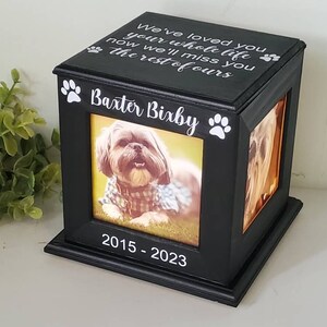 Może przedstawiać: Czarne drewniane pudełko na zdjęcia z obrazkiem psa w środku. Pudełko ma odciski łap i napis "We've loved you your whole life now we'll miss you the rest of ours" na g&oacute;rze. Pudełko ma r&oacute;wnież napis "Baxter Bixby" i "2015-2023" z przodu.