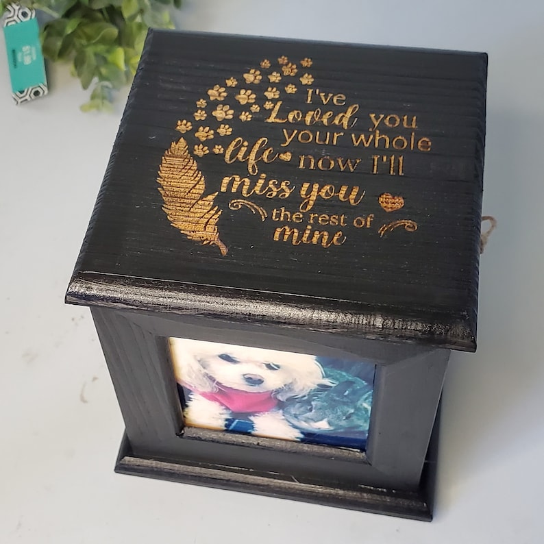 Puede incluir: Caja de madera negra con una inscripci&oacute;n grabada en oro que dice "I've Loved you your whole life now I'll miss you the rest of mine". La caja tiene un peque&ntilde;o marco de fotos con una imagen de un perro blanco.