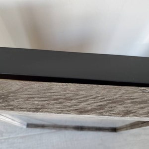 Puede incluir: Primer plano de una imagen enmarcada con un marco negro y un paspart&uacute; de madera de color gris claro.