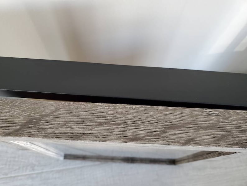 Puede incluir: Primer plano de una imagen enmarcada con un marco negro y un paspart&uacute; de madera de color gris claro.