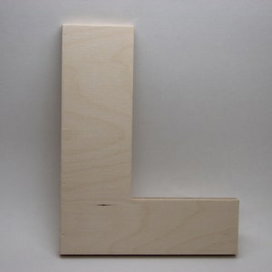 May include: A large, unfinished, wooden letter L. The letter is made of plywood and has a natural wood color.