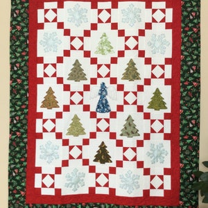May include: A Christmas-themed quilt with a white and red checkered pattern. The quilt features appliqued Christmas trees, snowflakes, and an angel. The border is green with small Christmas trees.