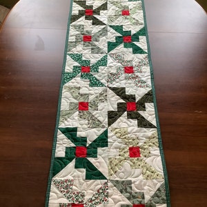Peut inclure: Un chemin de table vert et blanc avec un motif répété de carrés rouges et de carrés de tissu vert et blanc. Le chemin de table a une bordure verte.