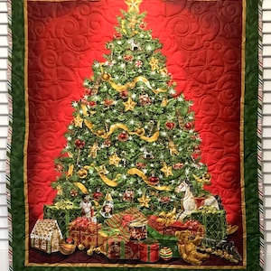 May include: A quilted Christmas tree wall hanging with a green border and a red background. The tree is decorated with ornaments, lights, and ribbons. There are presents and toys at the base of the tree.