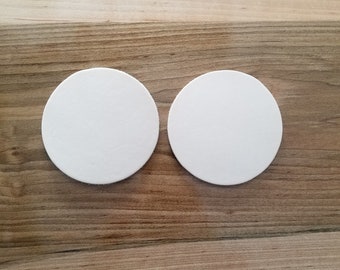 May include: Two white round coasters on a wood surface.