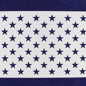 May include: A white stencil featuring a pattern of 50 dark blue stars, arranged in rows and columns. The stencil is rectangular and has text in the upper right and left corners. The background is a solid dark blue.