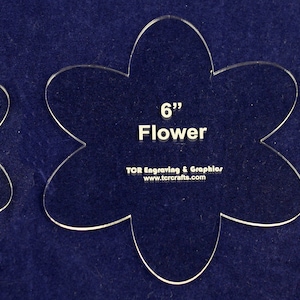 May include: Three clear plastic flower-shaped stencils, 4 inches, 5 inches, and 6 inches in diameter. The stencils are on a blue background.
