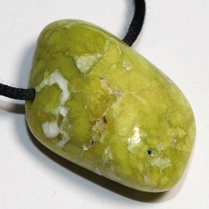 Peut inclure: Un pendentif en pierre verte et blanche sur un cordon noir. La pierre a un motif marbré et une forme irrégulière.
