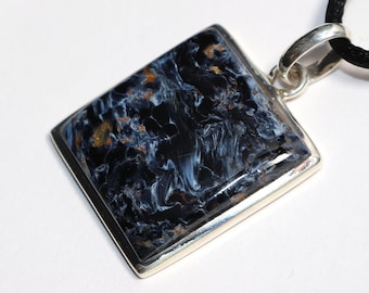 May include: A silver pendant with a square blue and black tiger's eye gemstone. The pendant is on a black cord.