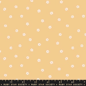 May include: A yellow fabric with a white floral pattern. The flowers have pink centers. The fabric has a repeating pattern of small white flowers with pink centers on a yellow background.