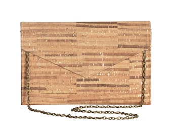 Pode incluir: Uma bolsa de mão de cortiça com uma corrente de ouro. A bolsa tem uma superfície de cortiça texturizada e um fecho de aba.