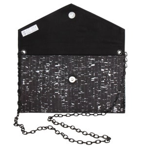 Pode incluir: Clutch preta de corti&ccedil;a com uma al&ccedil;a de corrente prateada. A clutch tem um forro de tecido preto e um pequeno fecho de bot&atilde;o prateado. A clutch tem uma etiqueta que diz "Que Sera Handmade Accessories".