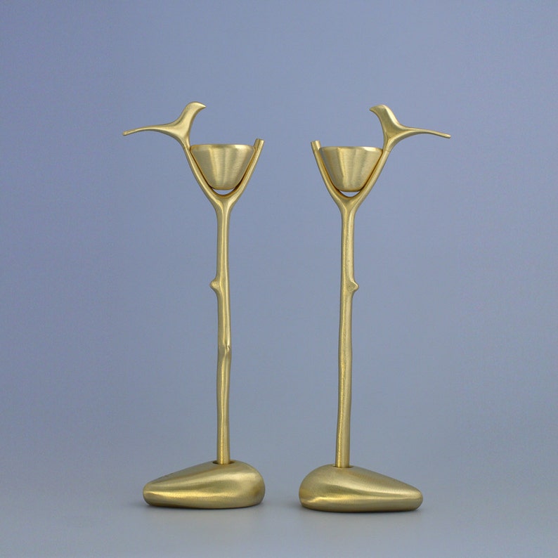 Puede incluir: Un par de candelabros de metal dorado con forma de ramas con un p&aacute;jaro posado en cada rama. Cada rama tiene un peque&ntilde;o cuenco en la parte superior para sostener una vela.