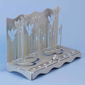 May include: A silver metal menorah with a unique design featuring stylized flowers. The menorah has nine candle holders and a central shamash holder.