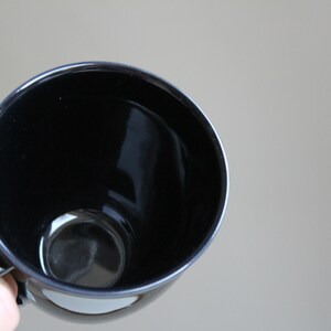 Puede incluir: Una taza de cer&aacute;mica negra con un acabado liso y brillante. La taza est&aacute; vac&iacute;a y lista para llenarse con una bebida caliente.