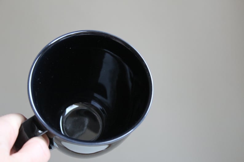 Puede incluir: Una taza de cer&aacute;mica negra con un acabado liso y brillante. La taza est&aacute; vac&iacute;a y lista para llenarse con una bebida caliente.