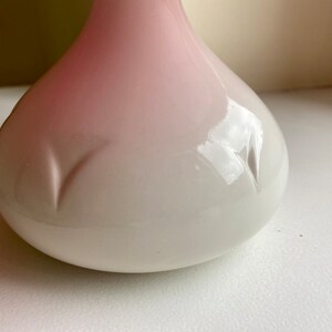 Może przedstawiać: Biały ceramiczny wazon z r&oacute;żowym ombre. Wazon ma zaokrąglony, kulisty kształt z gładkim, błyszczącym wykończeniem.
