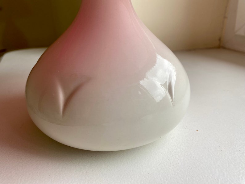 Może przedstawiać: Biały ceramiczny wazon z r&oacute;żowym ombre. Wazon ma zaokrąglony, kulisty kształt z gładkim, błyszczącym wykończeniem.