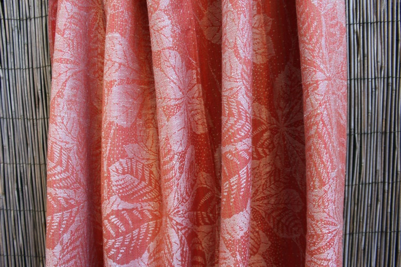 May include: A close-up of a coral-colored fabric with a white floral pattern. The fabric has a soft, textured feel and is perfect for curtains, upholstery, or clothing.