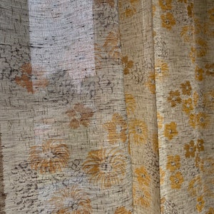 May include: A pair of sheer curtains with a floral pattern in shades of beige and yellow.