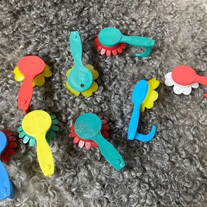 May include: Assortment of colorful plastic flower-shaped hair brushes with a variety of colors including red, blue, yellow, and green.