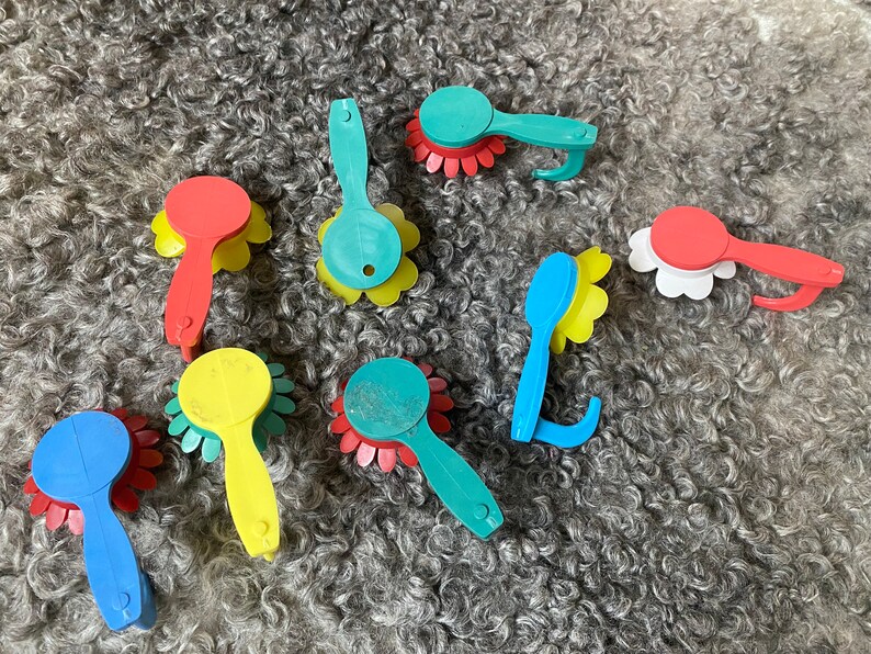 May include: Assortment of colorful plastic flower-shaped hair brushes with a variety of colors including red, blue, yellow, and green.