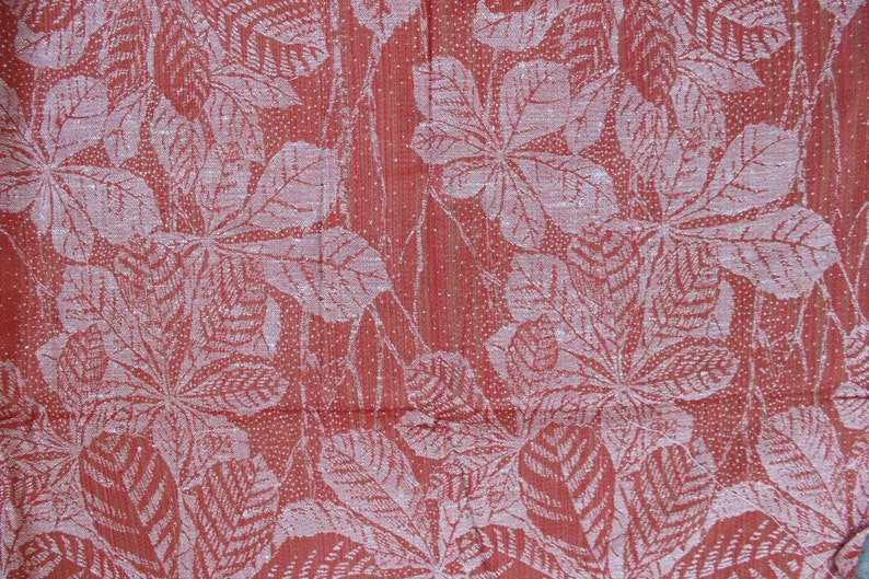 May include: Red fabric with a white embossed pattern of leaves. The leaves are arranged in a repeating pattern.