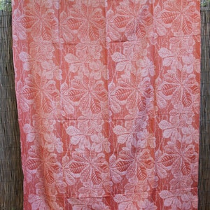 May include: A pink fabric with a white leaf pattern. The fabric is hanging on a woven fence.
