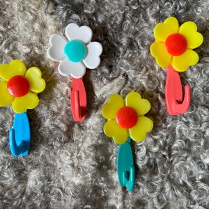 May include: Four flower-shaped hooks in yellow, white, and red with blue, green, and red hooks.