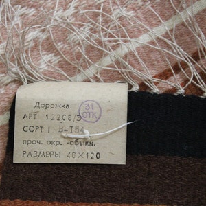 May include: A white tag with black text that reads "Дорожка APT 122C8/3 OPT 1 B-T54 проч. окр. -обыкн. РАЗМЕРЫ 40&times;120" and a red stamp that reads "31 ОТК".