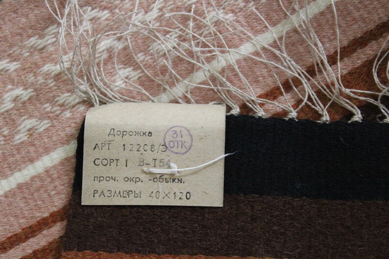 May include: A white tag with black text that reads "Дорожка APT 122C8/3 OPT 1 B-T54 проч. окр. -обыкн. РАЗМЕРЫ 40&times;120" and a red stamp that reads "31 ОТК".