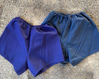 Pode incluir: Dois pares de calções desportivos, um em azul escuro e outro em azul marinho. Ambos os calções têm uma cintura elástica.
