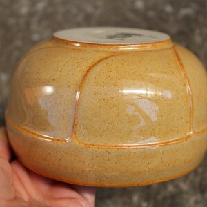 May include: A ceramic bowl with a light brown glaze and a slightly textured surface. The bowl has a rounded shape with four distinct sections.