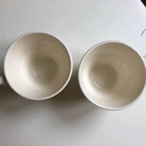 Peut inclure: Deux tasses &agrave; caf&eacute; en c&eacute;ramique blanche avec un design simple. Les tasses sont vides et ont une finition lisse et brillante.
