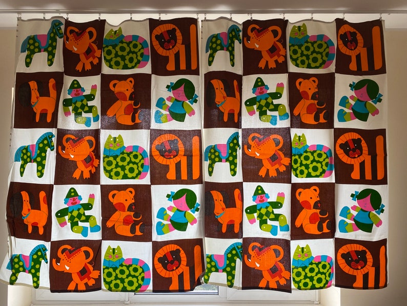 May include: A pair of brown and white curtains with a checkered pattern featuring colorful cartoon animals and figures. The animals include a lion, elephant, cat, and horse. The figures include a clown and a girl.