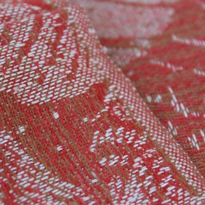 May include: Close-up of a red and white woven fabric with a textured pattern. The fabric has a soft, fuzzy texture.