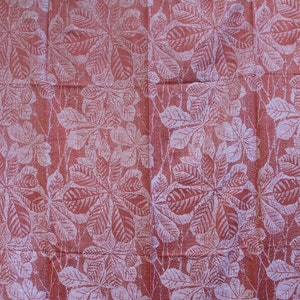 May include: A red fabric with a white leaf pattern. The leaves are arranged in a repeating pattern and have a slightly textured look.