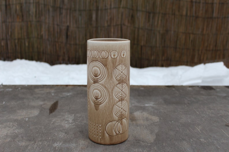 K&ouml;nnte beinhalten: Eine Keramikvase mit hellbrauner Glasur und einem geometrischen Muster aus Kreisen und Ringen.