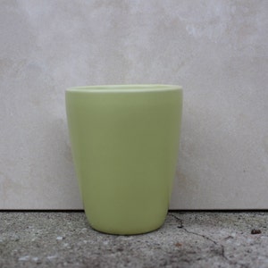 Puede incluir: Un vaso de plástico verde claro con una superficie lisa.