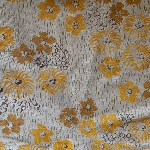 May include: A white fabric with a repeating pattern of yellow stylized flowers. The fabric has a textured, woven appearance.