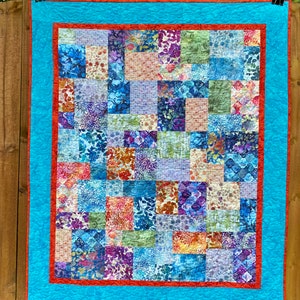 May include: A patchwork quilt with a blue and red border. The quilt is made up of many different squares of fabric, each with a different floral pattern.
