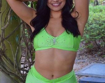 May include: A woman wearing a bright green two-piece dance outfit with rhinestones. The top is a halter style and the shorts are high-waisted.
