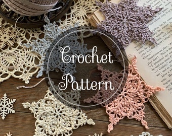 May include: Crochet pattern for a snowflake. The pattern is written on a book with the words "Crochet Pattern" in a circle. There are five crocheted snowflakes in various colors, including white, beige, and pink.