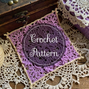 May include: A close-up of a crocheted square with a purple and cream color gradient. The square has a delicate lace pattern and is surrounded by a wooden box and crocheted doilies. The text "Crochet Pattern" is written in cursive on the square.