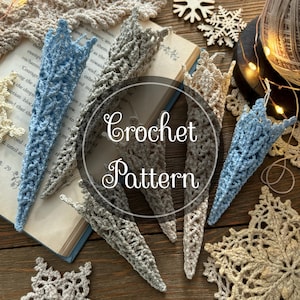 Puede incluir: Varios objetos de ganchillo hechos a mano en colores como azul, gris y beige, dispuestos sobre una superficie de madera. La imagen incluye el texto "Crochet Pattern", libros abiertos y copos de nieve decorativos.