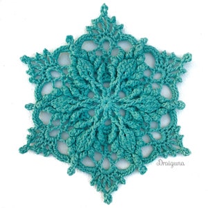 May include: A teal crocheted snowflake with a delicate, intricate design. The snowflake is made with a fine yarn and has a lacy appearance.