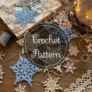 May include: Crochet pattern for a snowflake. The image shows several crocheted snowflakes in different colours, including blue, beige, and brown. The snowflakes are arranged on a wooden surface with a spool of yarn and wooden snowflakes.