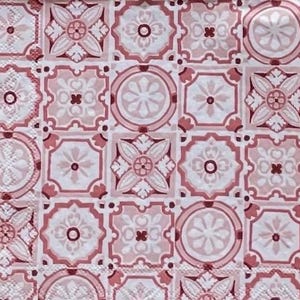 May include: Close-up of a patterned fabric featuring a repeating design of square tiles. Each tile showcases a floral or geometric motif in shades of pink and white, creating a symmetrical and decorative pattern. The overall aesthetic is vintage and elegant.
